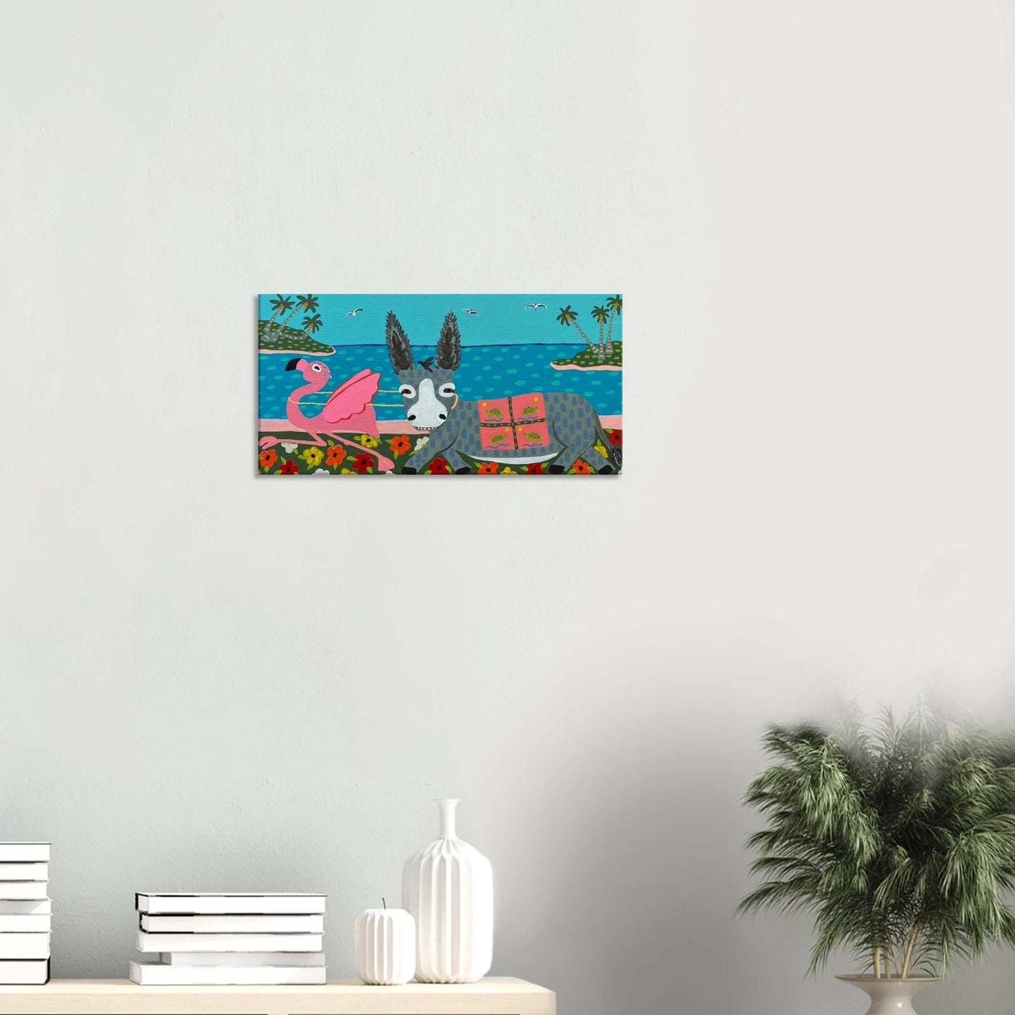 Canvas print of a donkey and flamingo on a beach scene hanging on a wall.