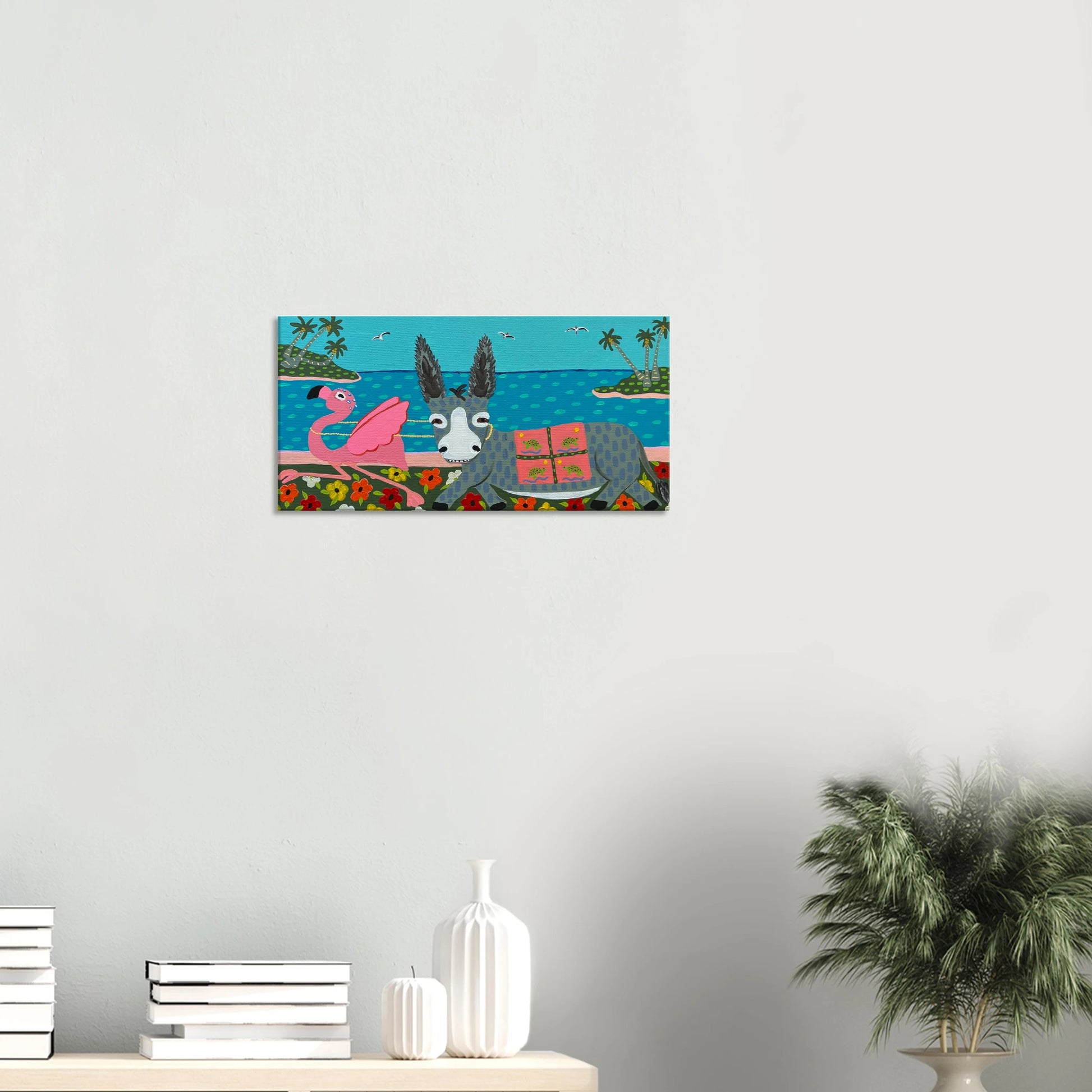 Canvas print of a donkey and flamingo on a beach scene hanging on a wall.